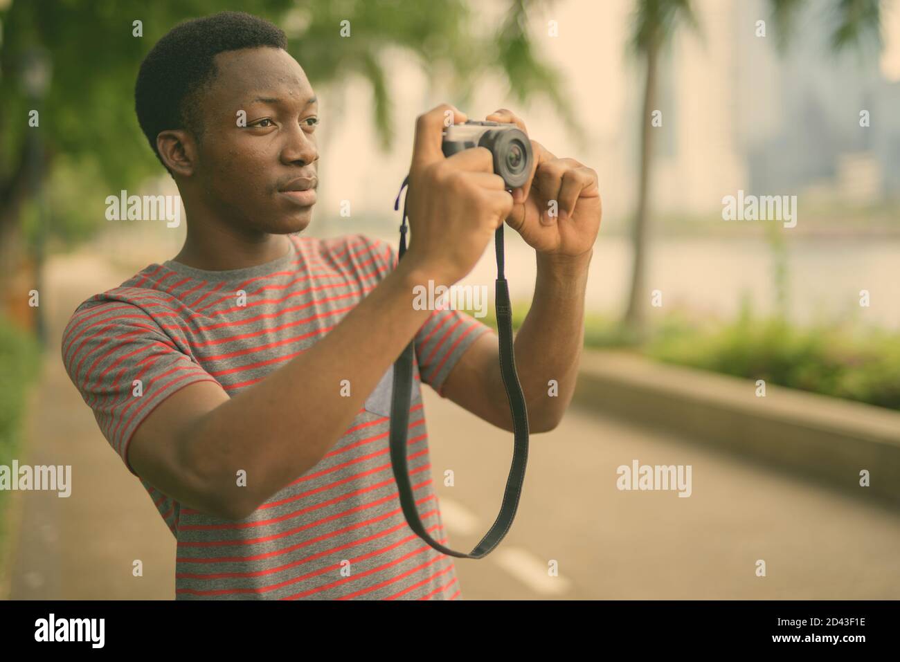 Young handsome African man using camera at the park Stock Photo - Alamy