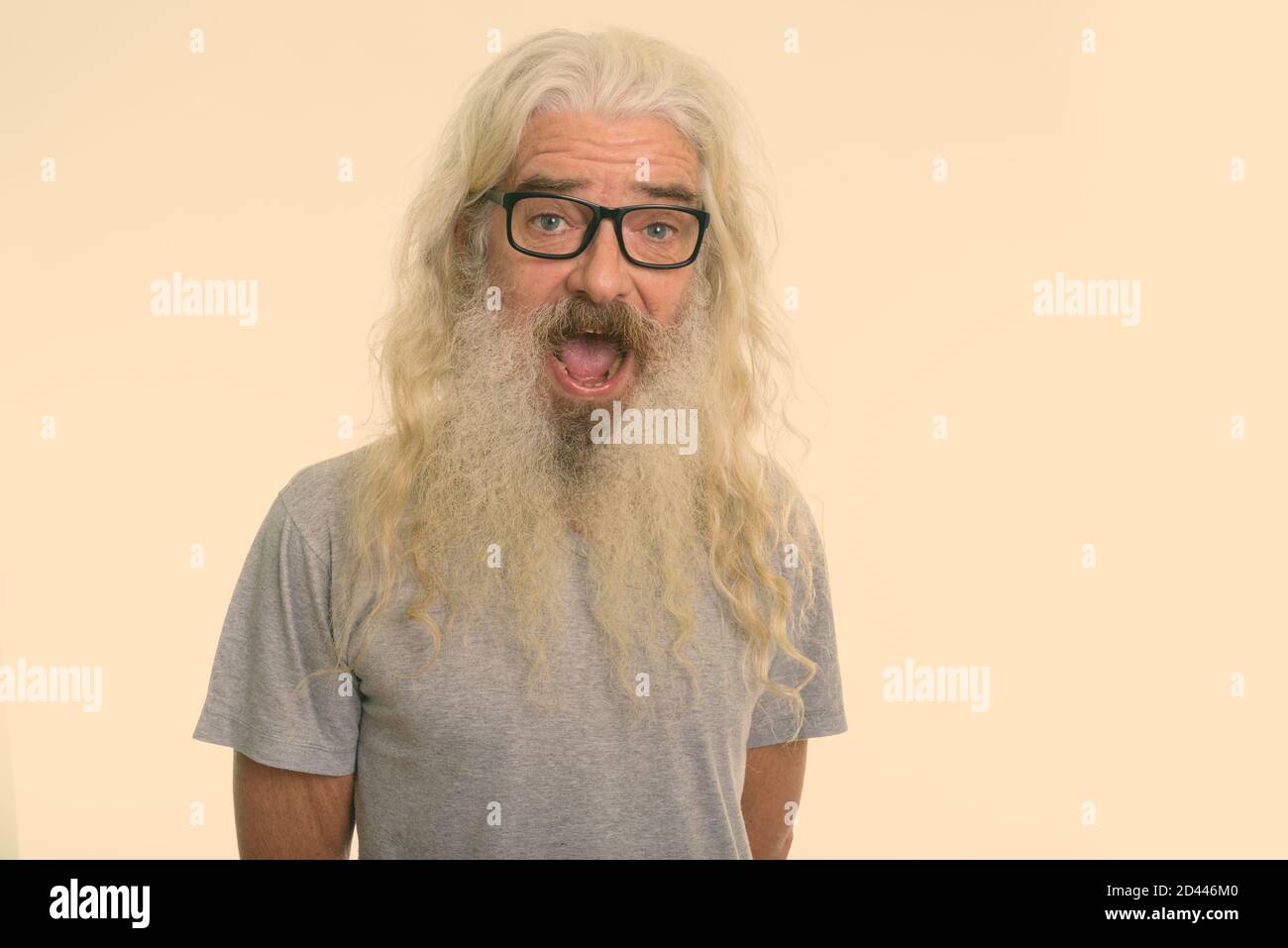 Studio shot of happy senior bearded man smiling and laughing while wearing eyeglasses Stock Photo