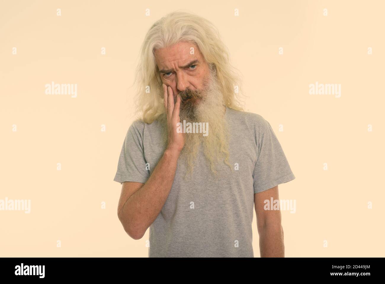 Studio shot of senior bearded man looking upset with hand on face Stock Photo