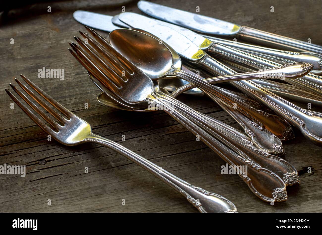 Fancy forks, knives and spoons are set out on a table, to be spread out for dinner Stock Photo