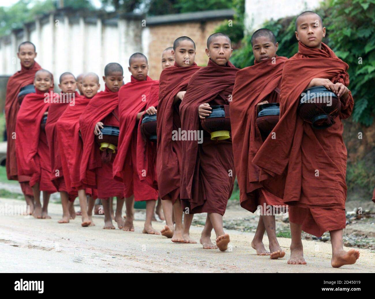 Young novice Buddhist Monks carry traditional bowls as they participate in  their daily morning walk to receive offerings from villagers in the central  Myanmar town of Kyaing Tong early May 13, 2001.