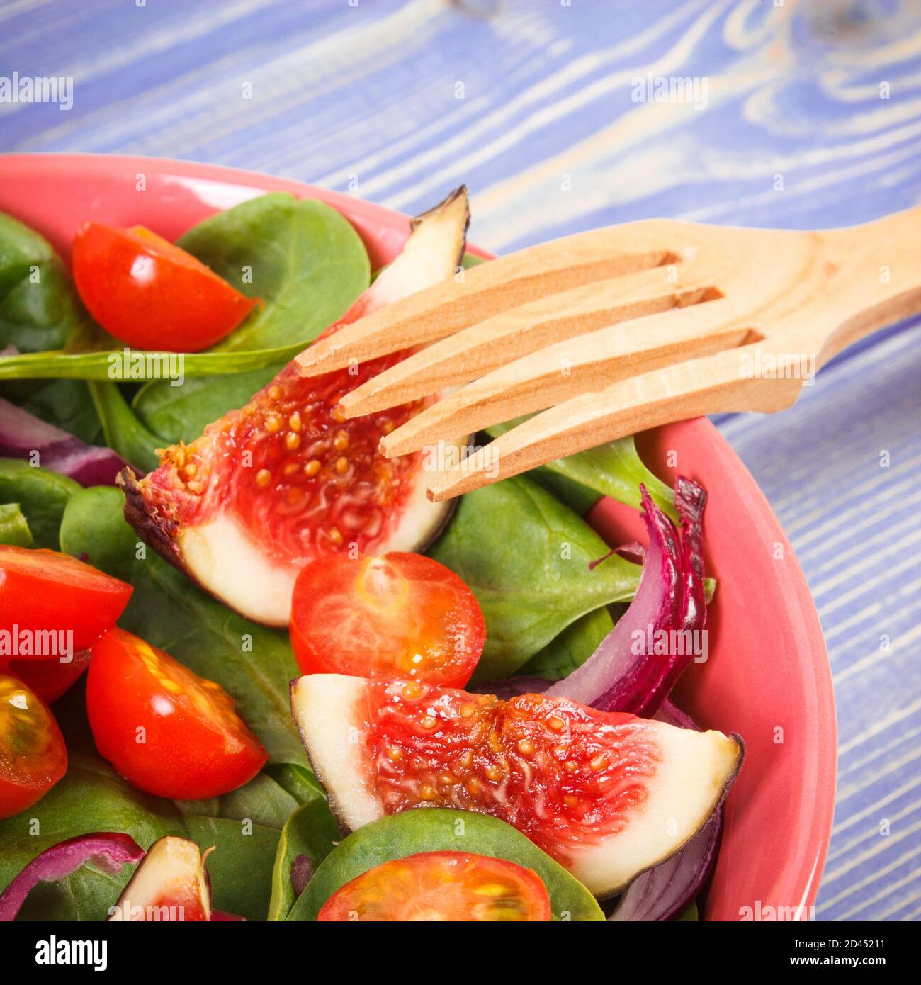 Fresh prepared fruit and vegetable salad and wooden fork in glass bowl