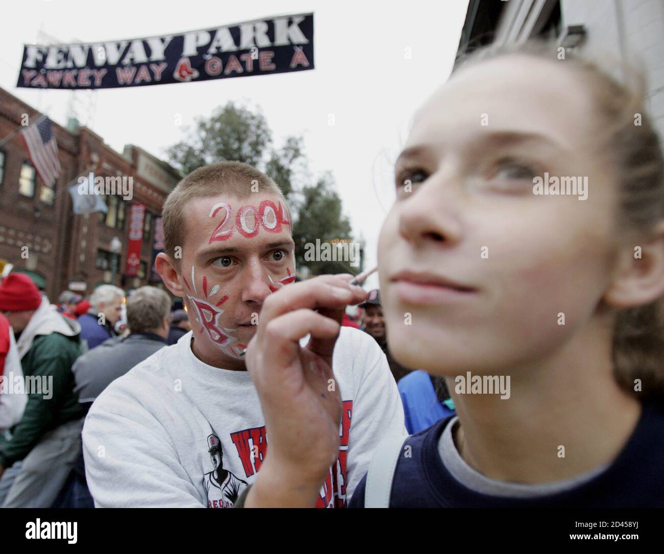 Boston Red Sox fan Robert Ectinter (L) paints the face of fellow fan  Lindsey Hagems before Game 1 of the World Series between the Red Sox and  St. Louis Cardinals at Fenway