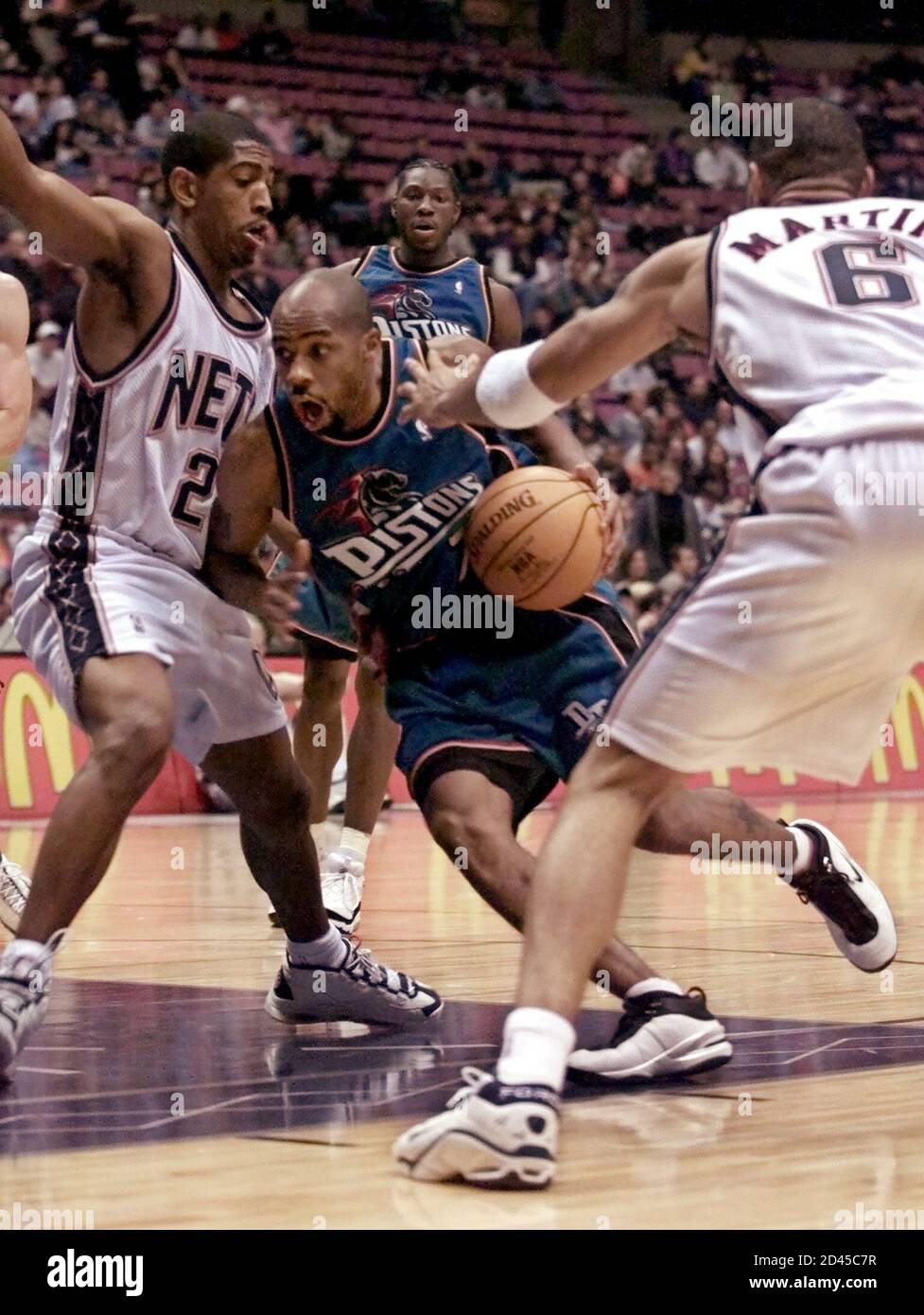 Detroit Pistons' guard Chucky Atkins (C) drives the lane between New Jersey Nets' forwards