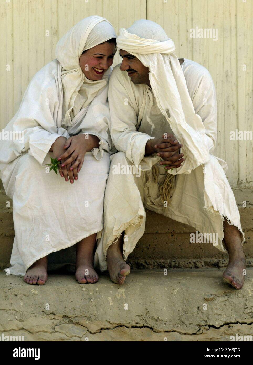 An Iraqi Mandean couple laugh together after their marriage on the Tigris river in Baghdad June 8, 2003. Iraqi devotees of an obscure religion who take John the Baptist as their central figure perform virginity tests on their brides and take a dip in the murky Tigris river every Sunday to purify the soul. Most of the worldAEs 20,000 or so Mandeans live in southern Iraq and southwestern Iran. REUTERS/Faleh Kheiber  CLH/ Stock Photo