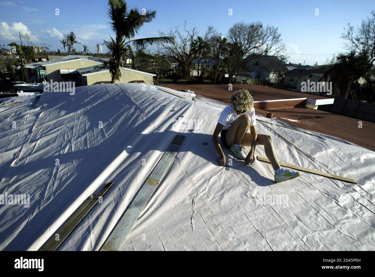 Lenora Quimby of Vero Beach, Florida uses duct tape to make repairs to the  roof of a friend's house in Fort Pierce, Florida September 27, 2004. The  roof had more tarps applied