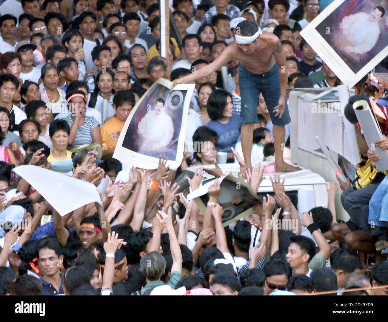 Suppporters of former president Joseph Estrada reach for posters of their fallen idol during a mass rally at a religious shrine in Manila April 29, 2001. Estrada, who is in police detention charged with economic plunder, called for a nationwide protest against the government of [Philippine President Gloria Macapagal Arroyo in a taped message played early Sunday.] Stock Photo