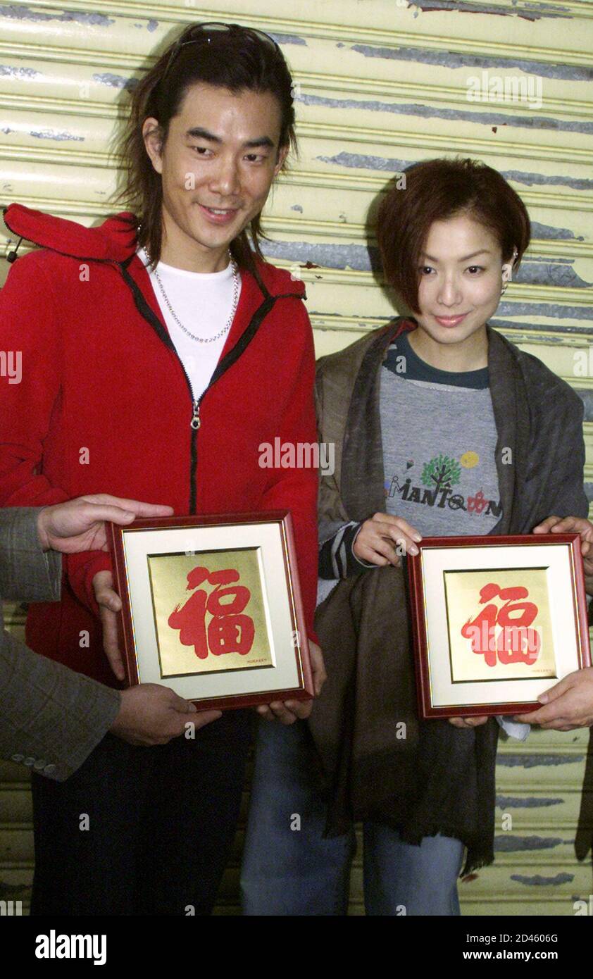 Hong Kong singer-actress Sammi Cheng (R) and Taiwanese singer-actor Richie Yum hold souvenirs which read 'Prosperity' before filming the romance film 'Marry a Rich Man' in Hong Kong November 13, 2001. The movie is due for release in January 2002. REUTERS/Kin Cheung  KC/CP Stock Photo