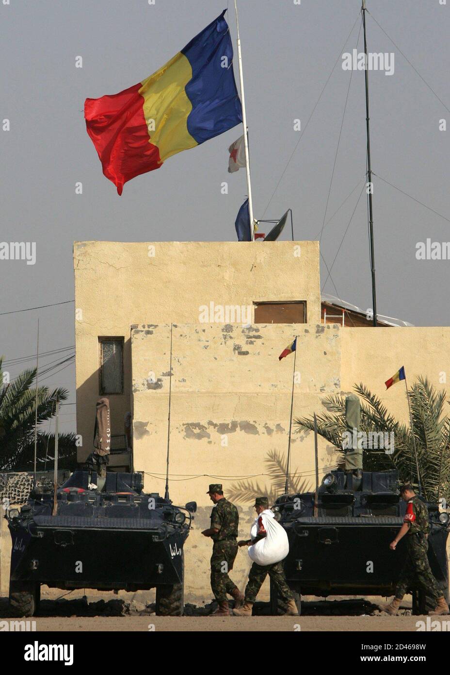 The Romanian flag waves in the wind on top of the headquarters building of the Romanian military force in Tallil Air Base.  The Romanian flag waves in the wind on top of the headquarters building of the Romanian military force in Tallil Air Base, approximately 310 km (192 miles) southeast of Baghdad, April 1, 2005. In the latest foreign hostage crisis, three Romanian journalists and their translator - who holds Iraqi, American and Romanian citizenship - were abducted this week in Baghdad. Insurgents later released a video showing them being held at gunpoint. REUTERS/Bob Strong Stock Photo