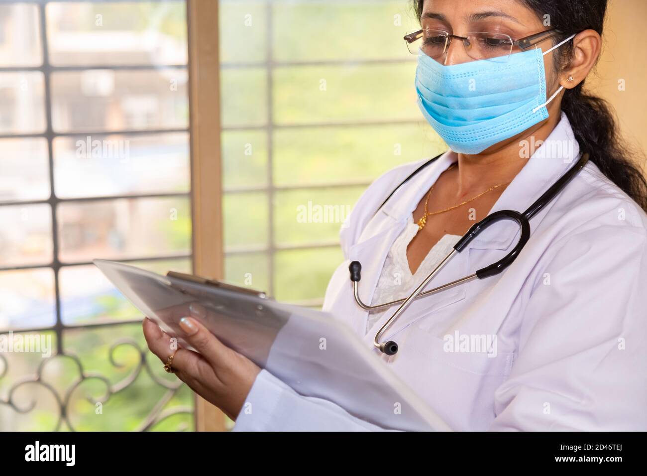 Indian female doctor wearing a stethoscope examine a medical report at ...