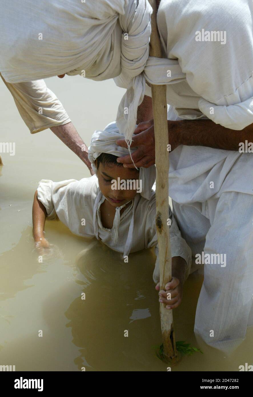 A young Iraqi Mandean boy is baptised in the Tigris river by a priest speaking the ancient Aramaic language during a wedding ceremony in Baghdad June 8, 2003. Iraqi devotees of an obscure religion who take John the Baptist as their central figure perform virginity tests on their brides and take a dip in the murky Tigris river every Sunday to purify the soul. Most of the worldAEs 20,000 or so Mandeans live in southern Iraq and southwestern Iran. REUTERS/Faleh Kheiber REUTERS  CLH/ Stock Photo