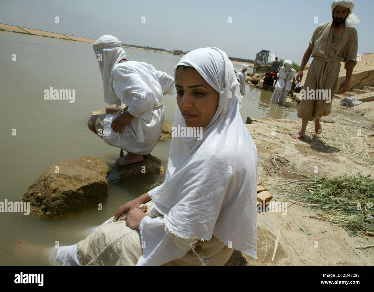 One of five Iraqi Mandean brides sits next to the Tigris river after her wedding ceremony in Baghdad June 8, 2003. Iraqi devotees of an obscure religion who take John the Baptist as their central figure perform virginity tests on their brides and take a dip in the murky Tigris river every Sunday to purify the soul. Most of the worldAEs 20,000 or so Mandeans live in southern Iraq and southwestern Iran. REUTERS/Faleh Kheiber REUTERS  CLH/ Stock Photo