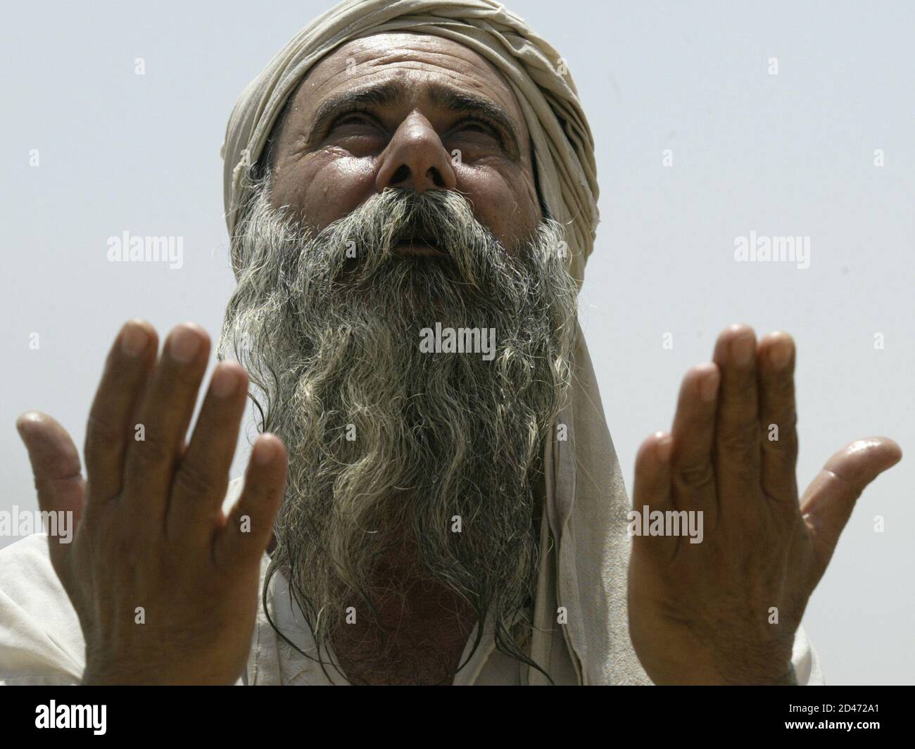 An Iraqi Mandean priest prays in the ancient Aramaic language during a marriage ceremony for five couples on the Tigris river in Baghdad June 8, 2003. Iraqi devotees of an obscure religion who take John the Baptist as their central figure perform virginity tests on their brides and take a dip in the murky Tigris river every Sunday to purify the soul. Most of the world's 20,000 or so Mandeans live in southern Iraq and southwestern Iran. Stock Photo