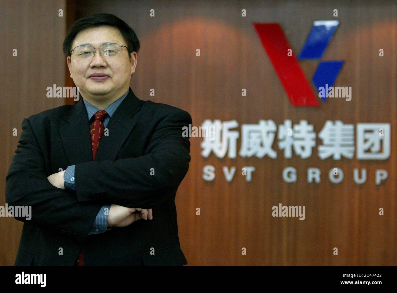 Yan Xiaoqun, 39-year old CEO of SVT Group, poses beside his company logo at their headquarters in Nanjing April 7, 2004. Not content with making washing machines and mobile phones, the company which he heads, the privately-held SVT Group, last year bought a football team, and is now setting up its own airline. With sales this year set to ratchet up growth in excess of 30 percent to $3 billion, an overseas listing, more foreign factories and international acquisitions are planned for the rest of the year and next. Picture taken April 7, 2004. REUTERS/Claro Cortes IV  CC Stock Photo