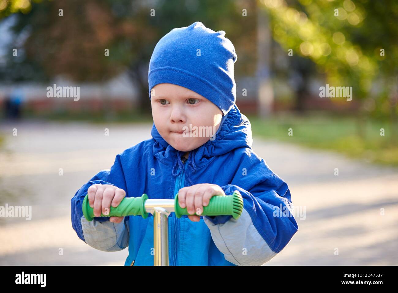 A twoyearold boy rides a scooter in the park in autumn Stock Photo Alamy