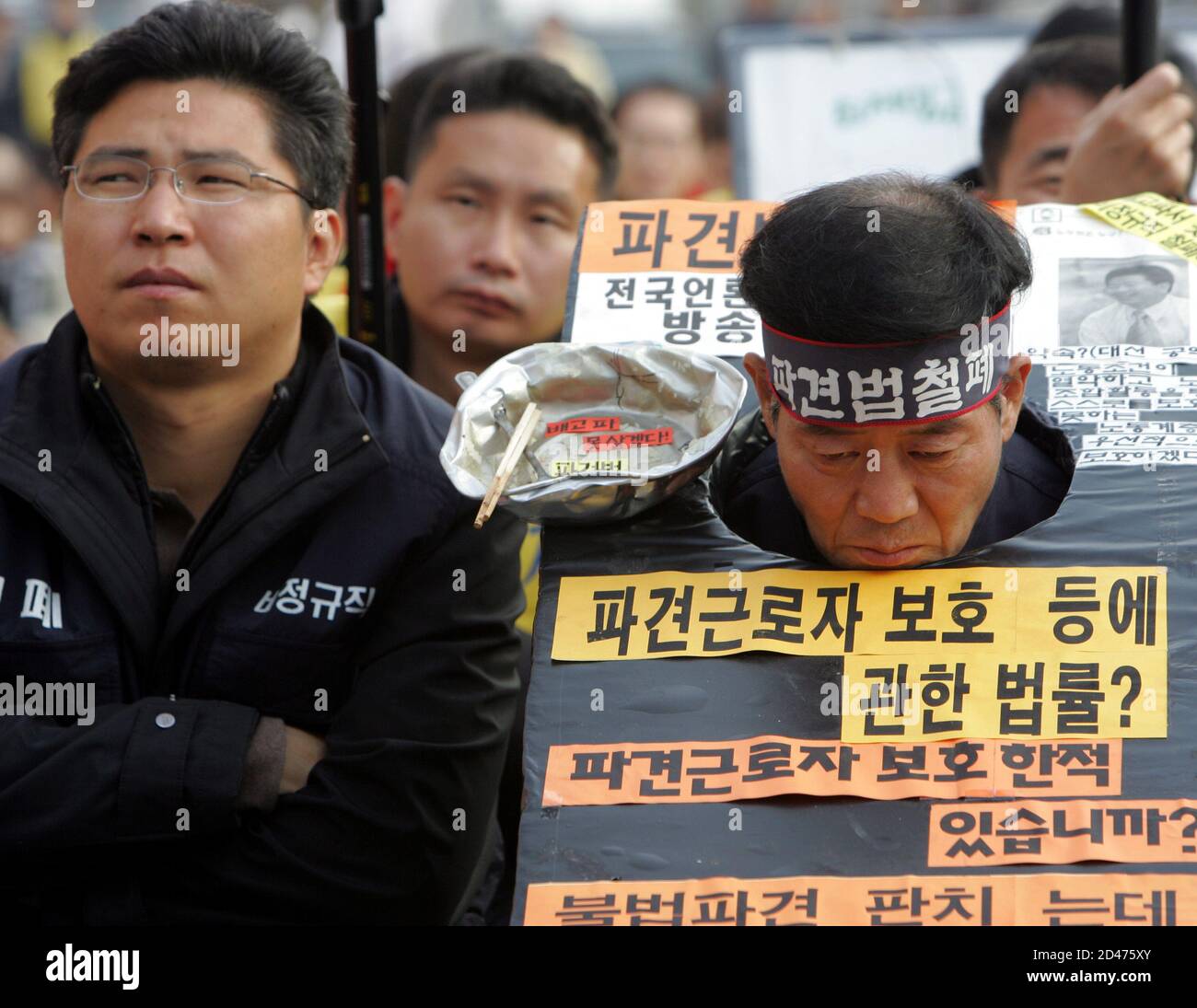 Wearing mock stocks and a bowl with chopsticks and a spoon, a South Korean temporary worker participates in a rally near parliament in Seoul November 24, 2004. About 400 unionised temporary workers rallied in Seoul on Wednesday to oppose a government-driven law, which they insist would worsen their working conditions. REUTERS/You Sung-Ho  YSH/ Stock Photo