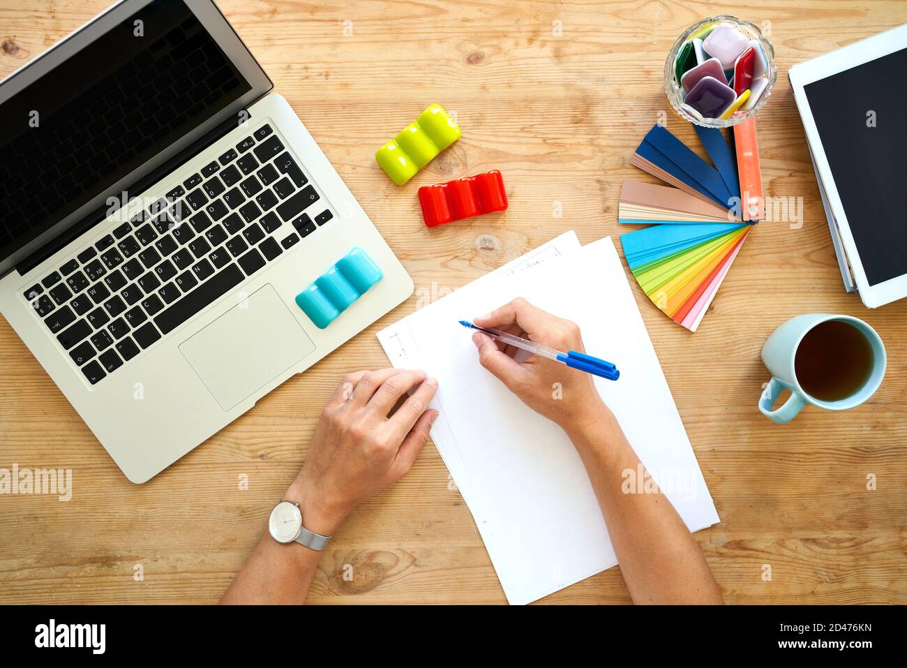 Designer workplace, top view. Home office - desk with laptop, hands with colourful set, Stock Photo