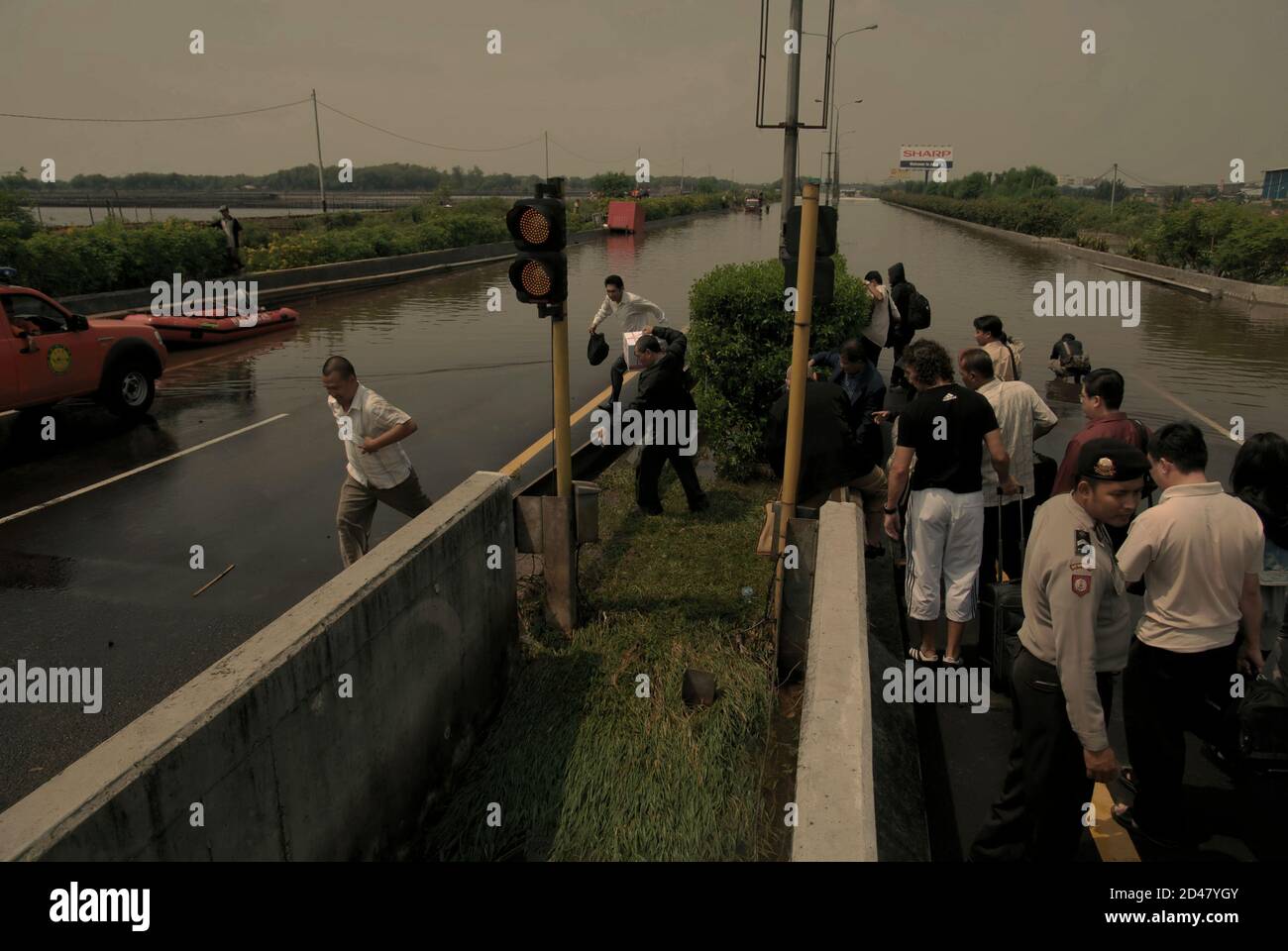 Airport shutter bus passengers moving in a hurry to reach another vehicle provided by police, after torrential rain has left the toll road flooded in Jakarta, Indonesia. Archival photo (2008). Stock Photo
