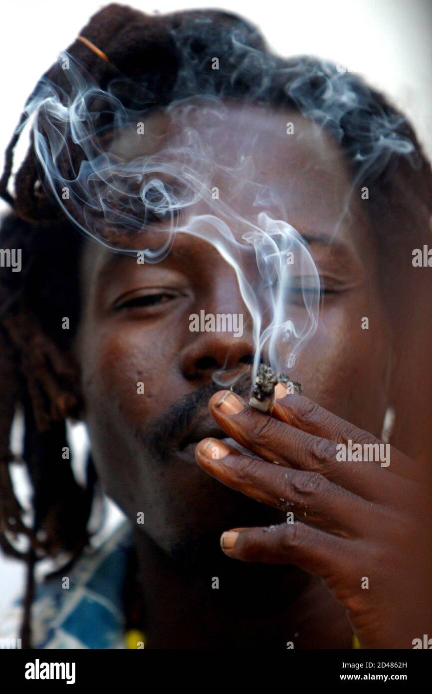 A member of an Ivorian Rastafarian community smokes marijuana during a music session called 'Naya Bingue' one day before the 24th anniversary of the death of reggae icon Bob Marley at the Rastafarian village of Virdi, south of the Ivorian capital Abidjan, May 10, 2005. Marley died on May 11, 1981.  Picture taken May 10, 2005. Stock Photo