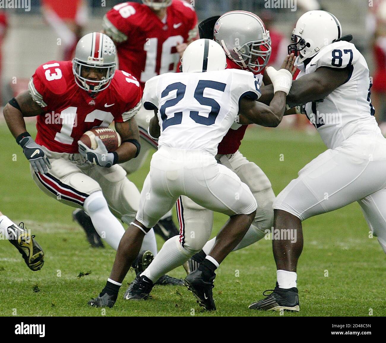 Ohio State University's freshman tailback Maurice Clarett (13) tries to  break through a hole early in the first quarter as teammate Brandon Joe  (rear right) blocks Penn State University's defensive end John