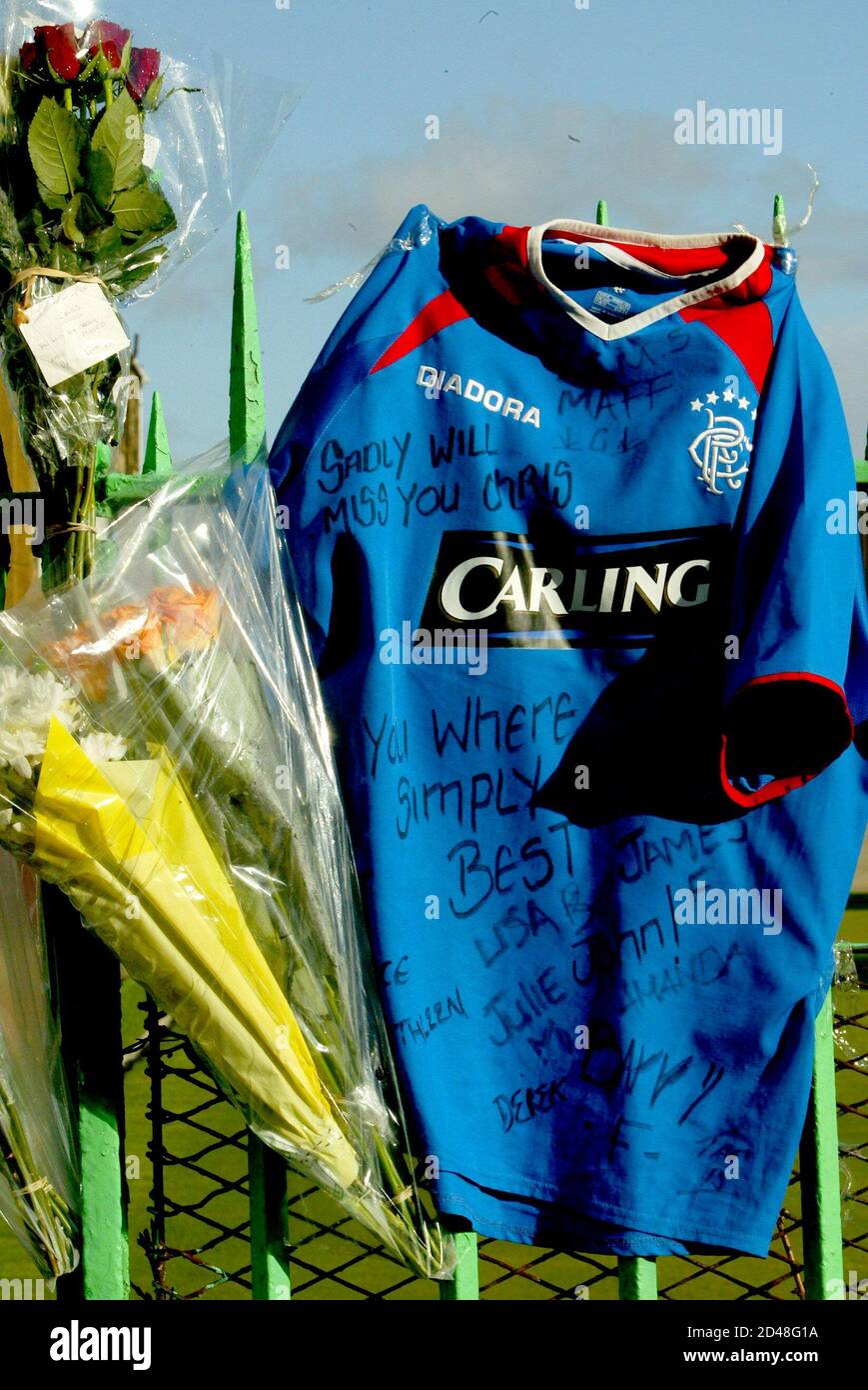 Flowers and a Rangers' football shirt hang from a fence in Kenmure Street, Glasgow, where 15-year-old murder victim Kriss Donald was snatched by a group of men near his home, March 17, 2004. Donald was snatched on Monday by five men said by police to be of Asian appearance, in southern Glasgow and his badly beaten body was found the next day behind a Celtic supporters' club in the east end of the city. REUTERS/Jeff J Mitchell  JJM/MD/THI Stock Photo