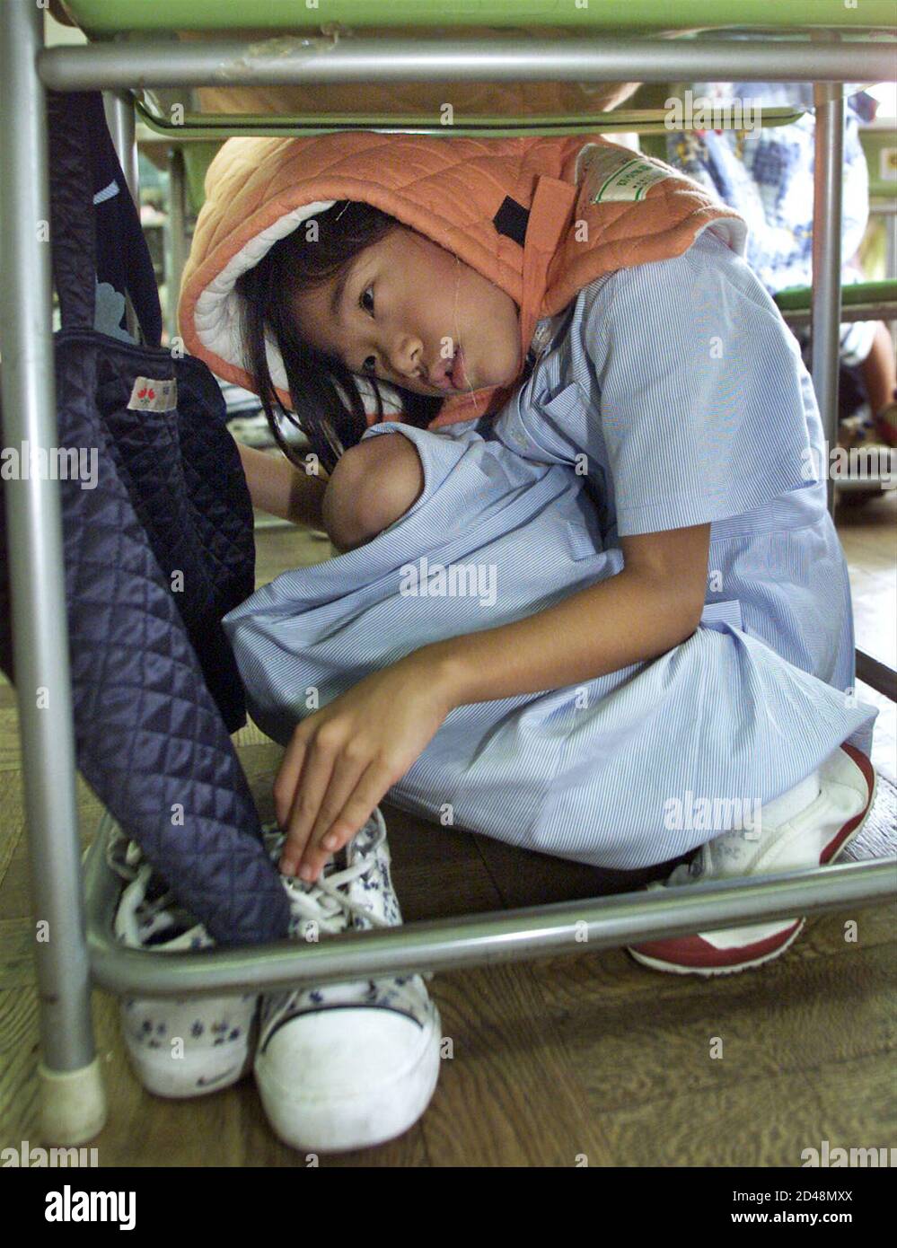A young Japanese girl in protective head gear crawls underneath her