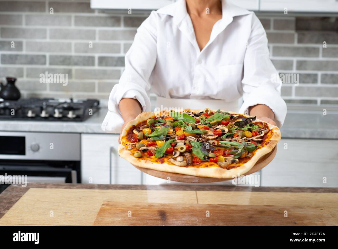Сhef demonstrates a readytoeat pizza without cheese. Vegan food Stock