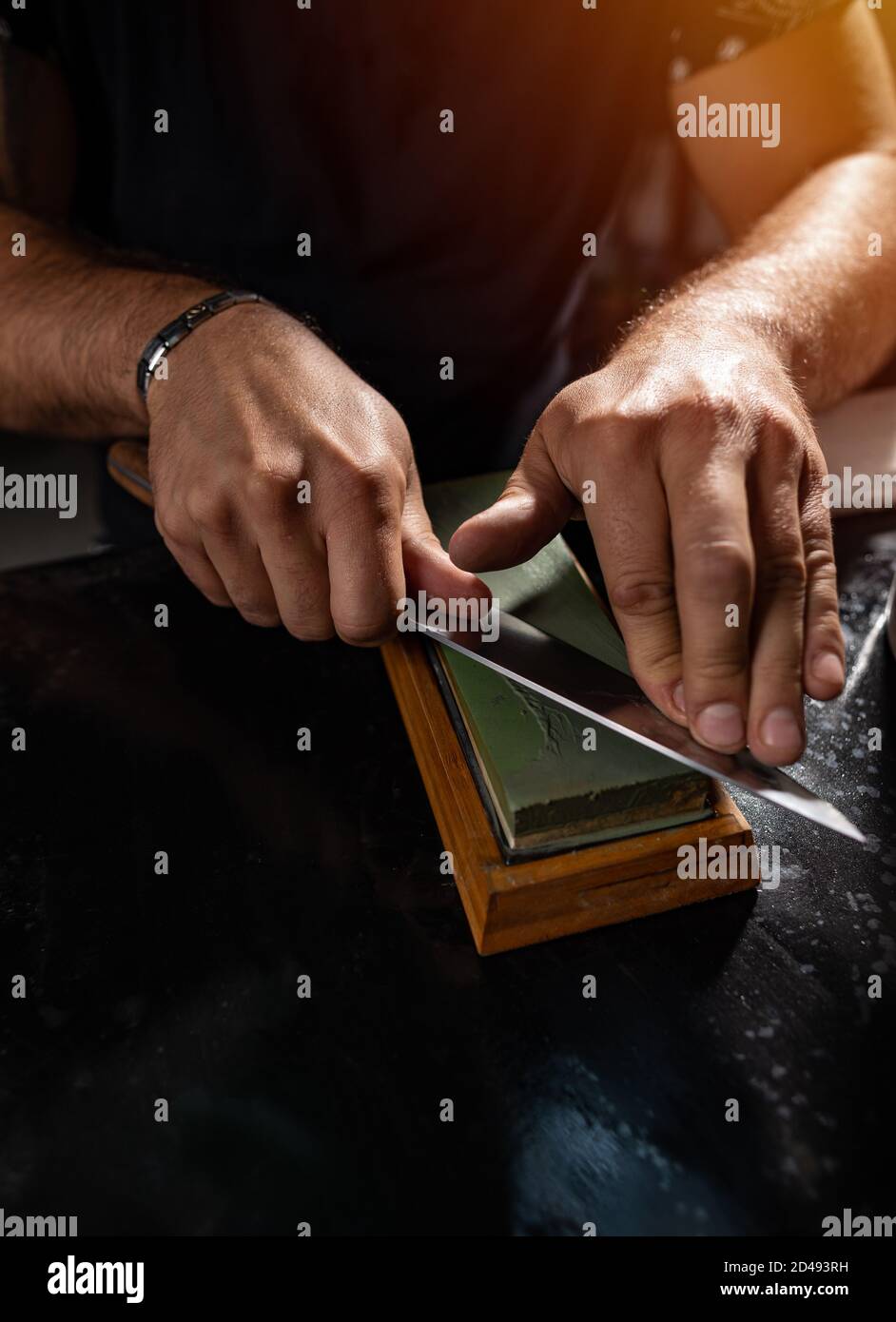 Sharpening the knife with whetstone, close up shot Stock Photo