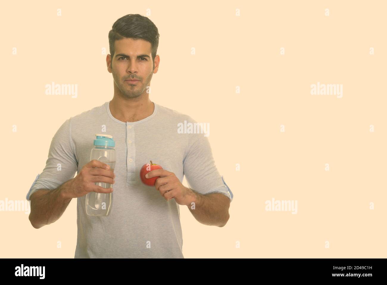 Young handsome Persian man holding water bottle and red apple Stock ...