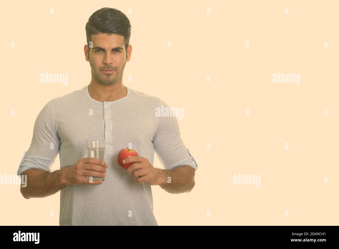 Young handsome Persian man holding glass of water and red apple Stock ...