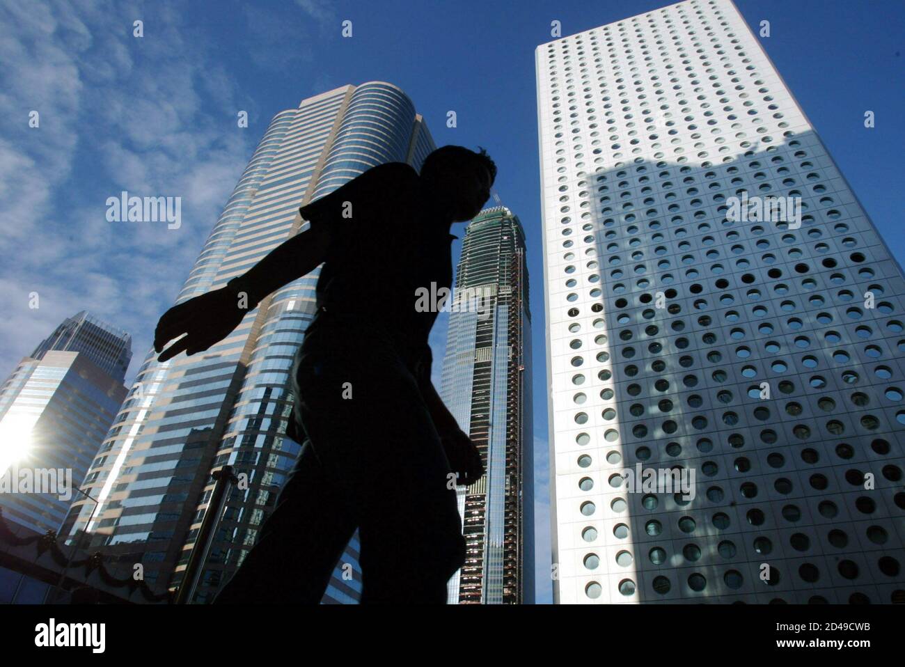 A man walks past buildings in central business district in Hong Kong December 16, 2002. [Hong Kong's unemployment rate stood at 7.1 percent in the three months to end November on a seasonally adjusted basis, the government said on Monday. The figure stood at 7.2 percent in the August to October period.] Stock Photo