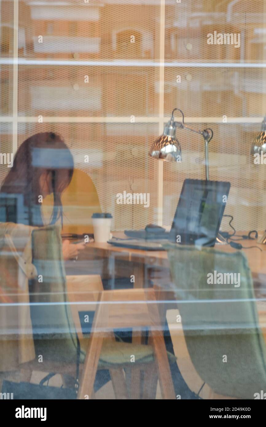 Kazan, Russia, September 16, 2020. A young woman is sitting at a laptop in the library. Side view through window glass Stock Photo