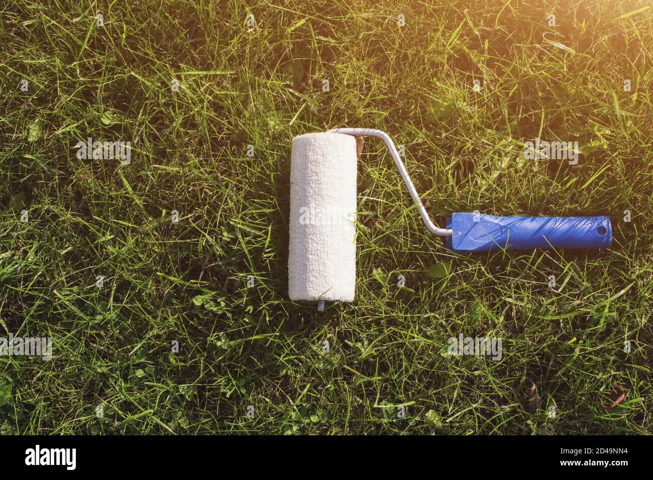Top view of a paint roller with an blue handle, that is painting a grassy strip using lawn as color. Ecological concept Stock Photo