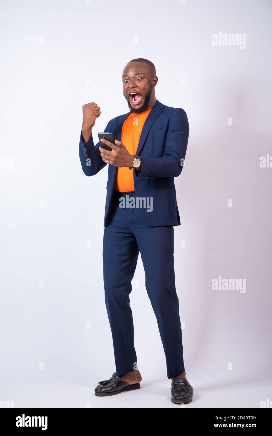 young african businessman looking at his phone looks very surprised and celebrates Stock Photo