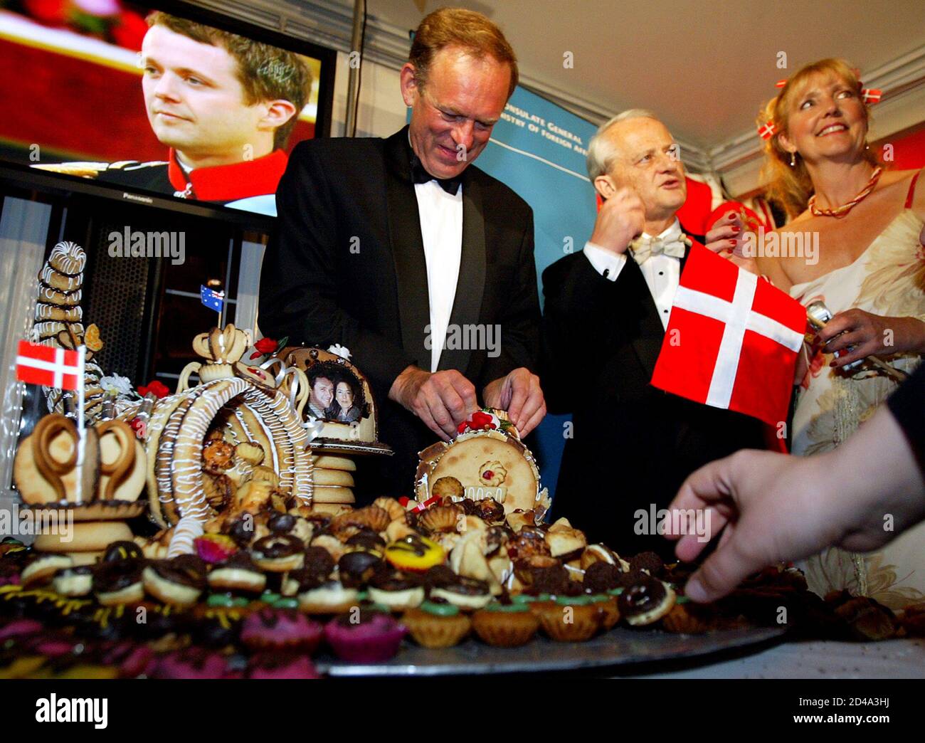 DANISH CROWN PRINCE FREDERIK SEEN ON A TELEVISION SCREEN AS PEOPLE EAT A WEDDING CAKE AT A PARTY FOR THE ROYAL WEDDING IN SYDNEY. Danish Crown Prince Frederik (L) is seen