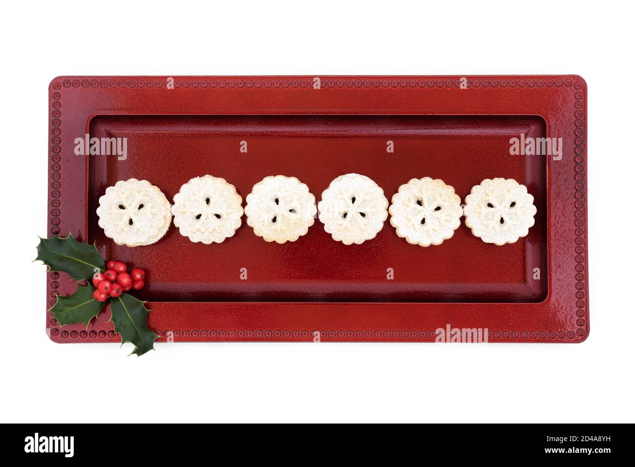 Homemade Christmas mince pies on a red plate with winter berry holly on ...
