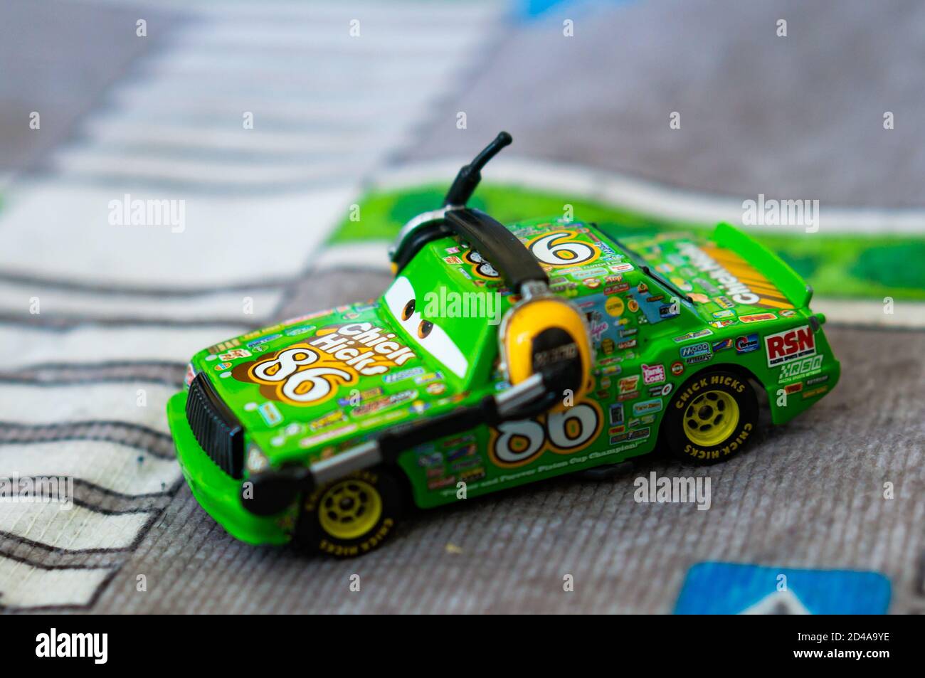 POZNAN, POLAND - Oct 03, 2020: Green Disney Pixar Mattel Chick Hicks toy model car with number 86 wearing headphones with microphone on a play road ma Stock Photo