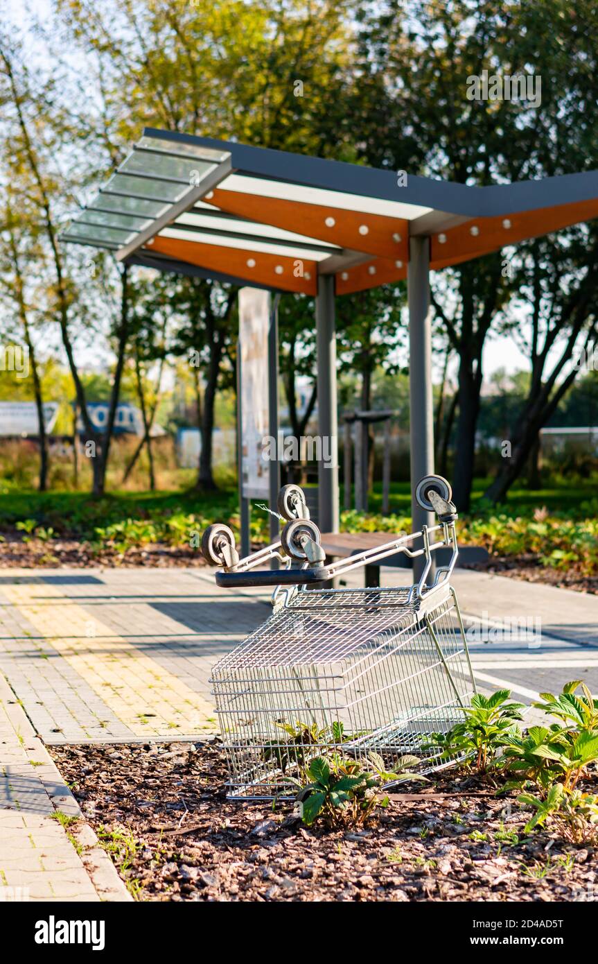 POZNAN, POLAND - Oct 03, 2020: Metal shopping cart laying upside down on the ground in front of a exposition stop in the Rataje park. Stock Photo