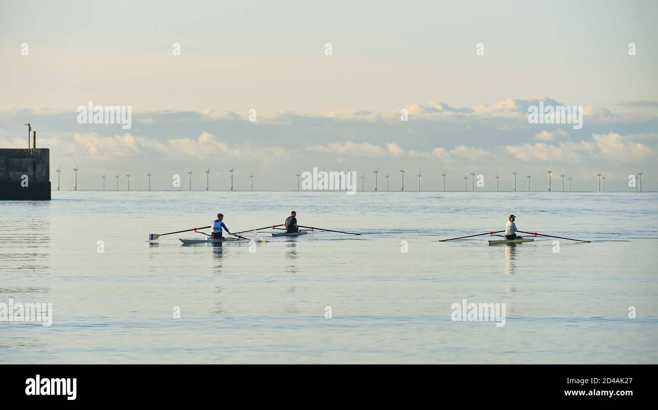Brighton UK 9th October 2020 - Rowers and scullers from Shoreham Rowing Club enjoy a beautiful calm sunny morning at Shoreham harbour near Brighton  . In the background the Rampion Wind Farm can be seen on the horizon : Credit Simon Dack / Alamy Live News Stock Photo