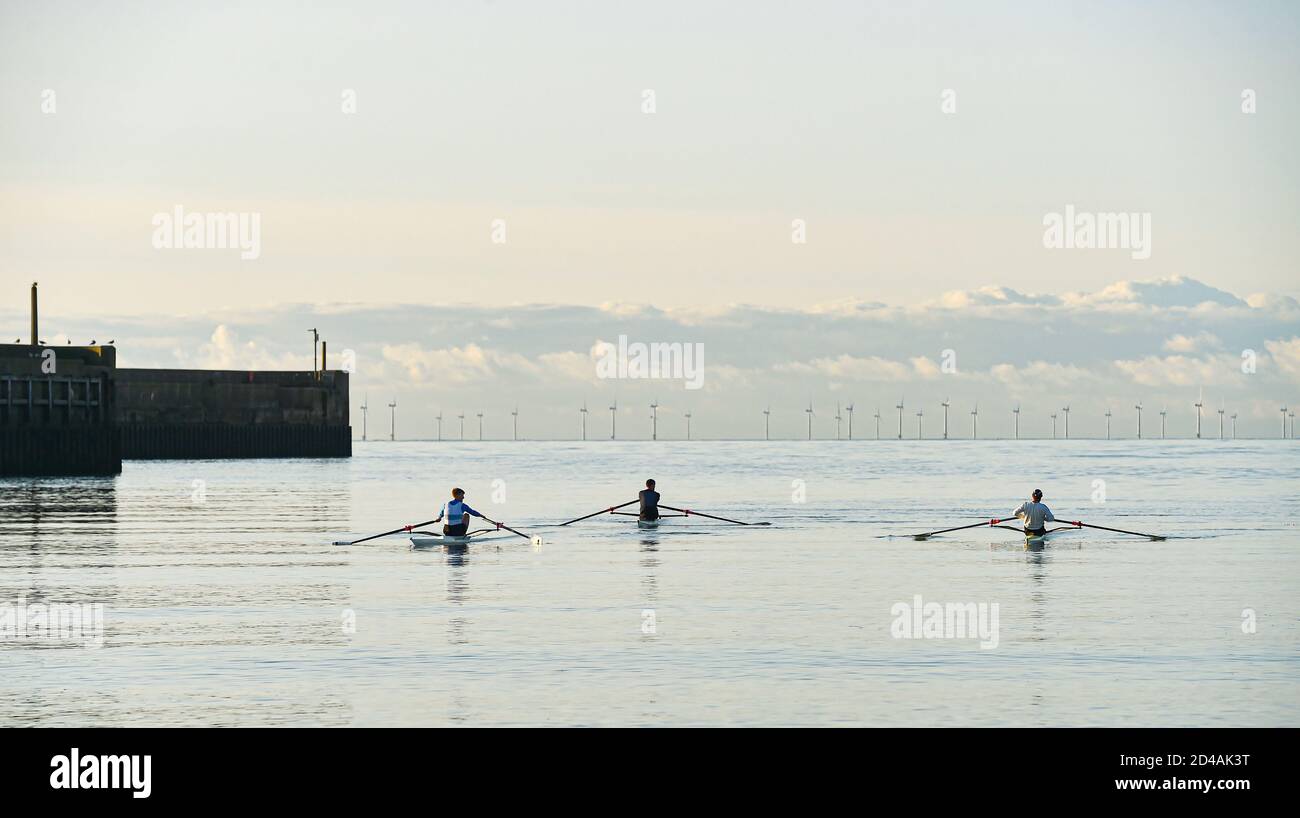 Brighton UK 9th October 2020 - Rowers and scullers from Shoreham Rowing Club enjoy a beautiful calm sunny morning at Shoreham harbour near Brighton  . In the background the Rampion Wind Farm can be seen on the horizon : Credit Simon Dack / Alamy Live News Stock Photo