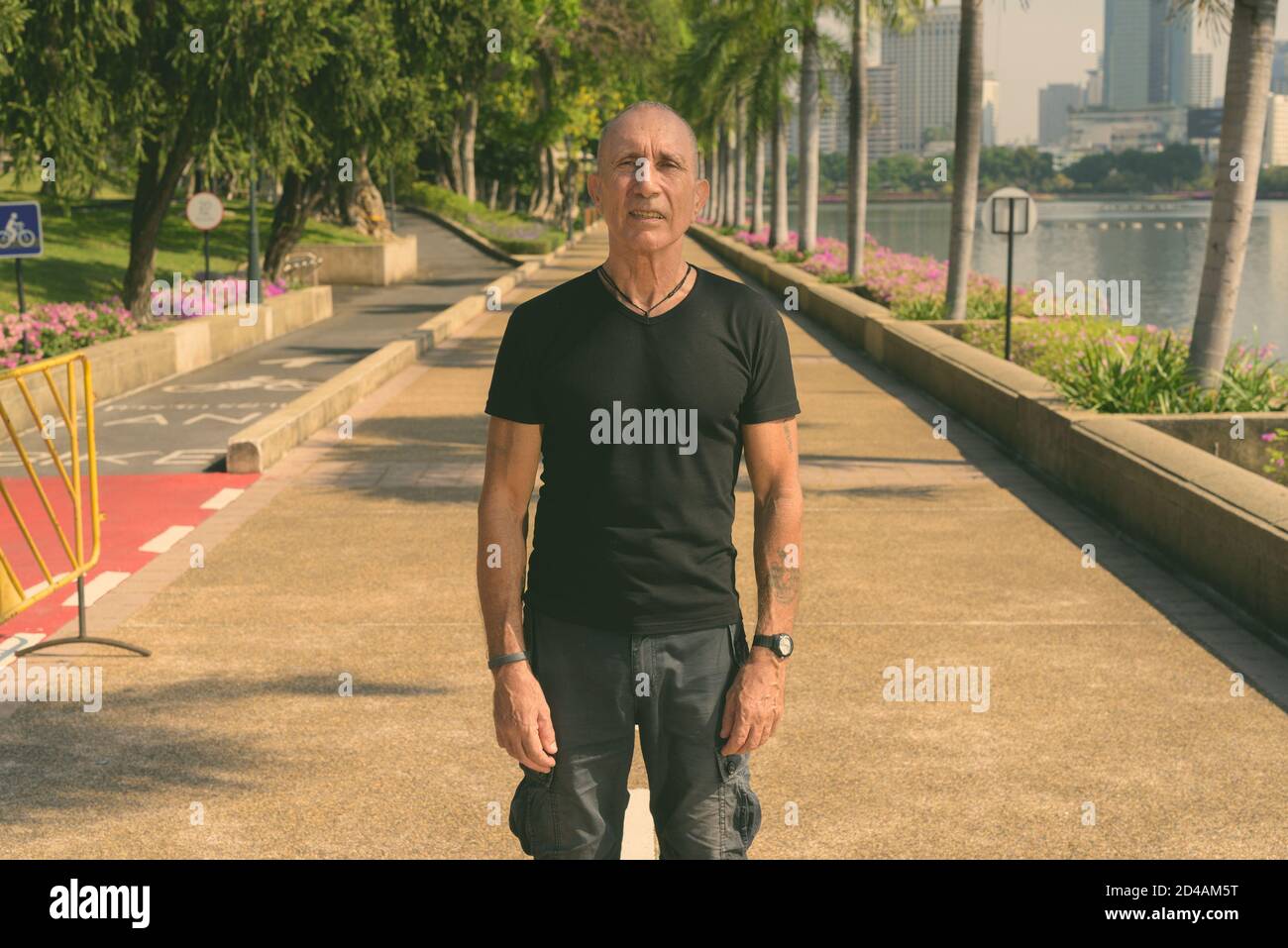 Bald senior tourist man standing at peaceful park in Bangkok Thailand Stock Photo