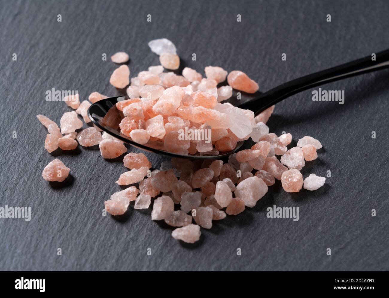 Angled shot of pink rock salt in a black spoon placed on a black background  Stock Photo - Alamy