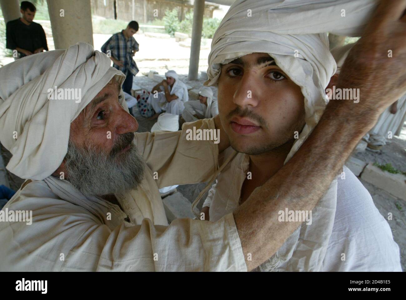HAn Iraqi Mandean priest wraps the head of a groom in cloth during a wedding ceremony for five couples, conducted in the ancient Aramaic language, on the Tigris river in Baghdad June 8, 2003. Iraqi devotees of an obscure religion who take John the Baptist as their central figure perform virginity tests on their brides and take a dip in the murky Tigris river every Sunday to purify the soul. Most of the worldAEs 20,000 or so Mandeans live in southern Iraq and southwestern Iran. REUTERS/Faleh Kheiber  CLH/ Stock Photo