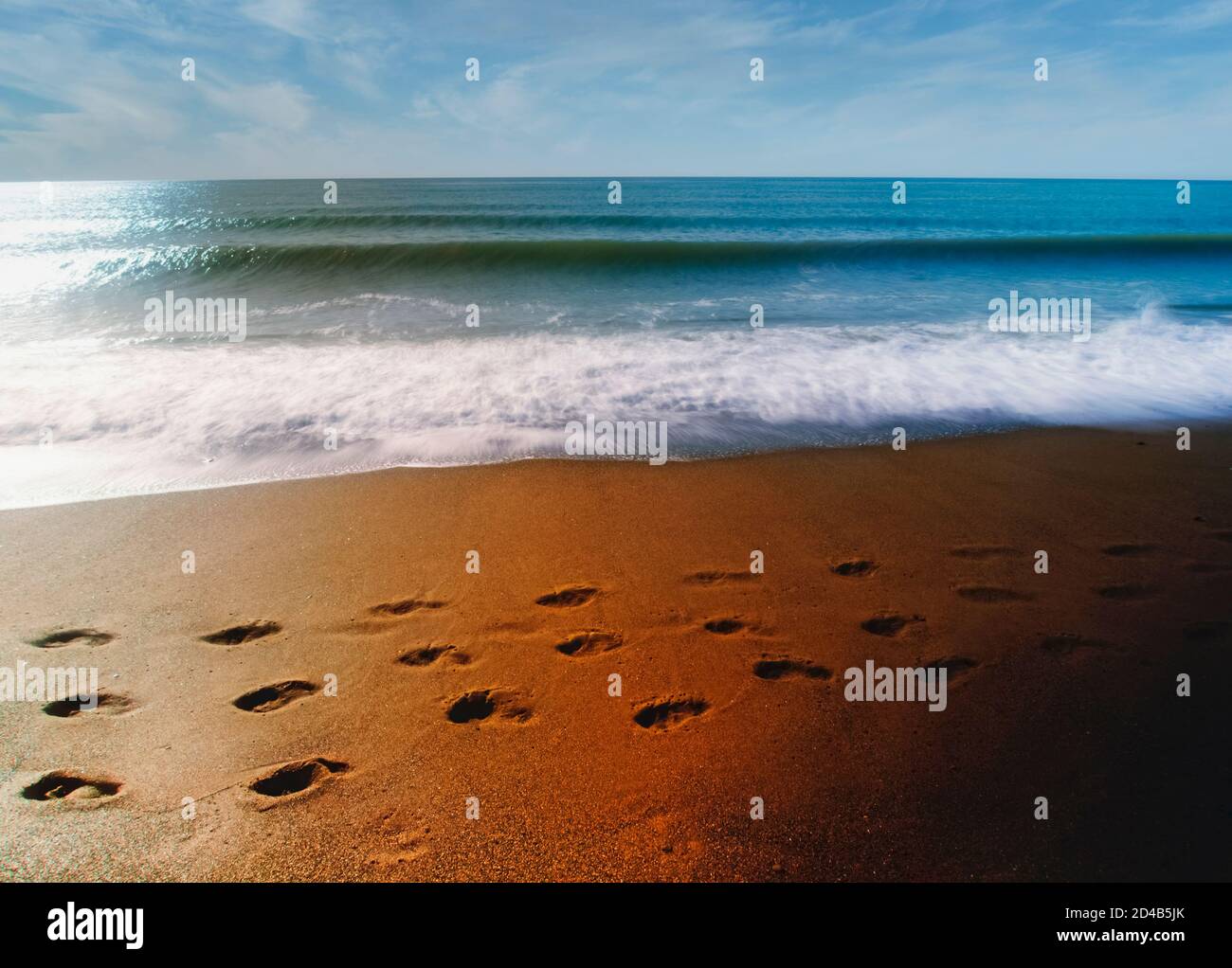 Footprints on beach.  Waves rolling in. Stock Photo