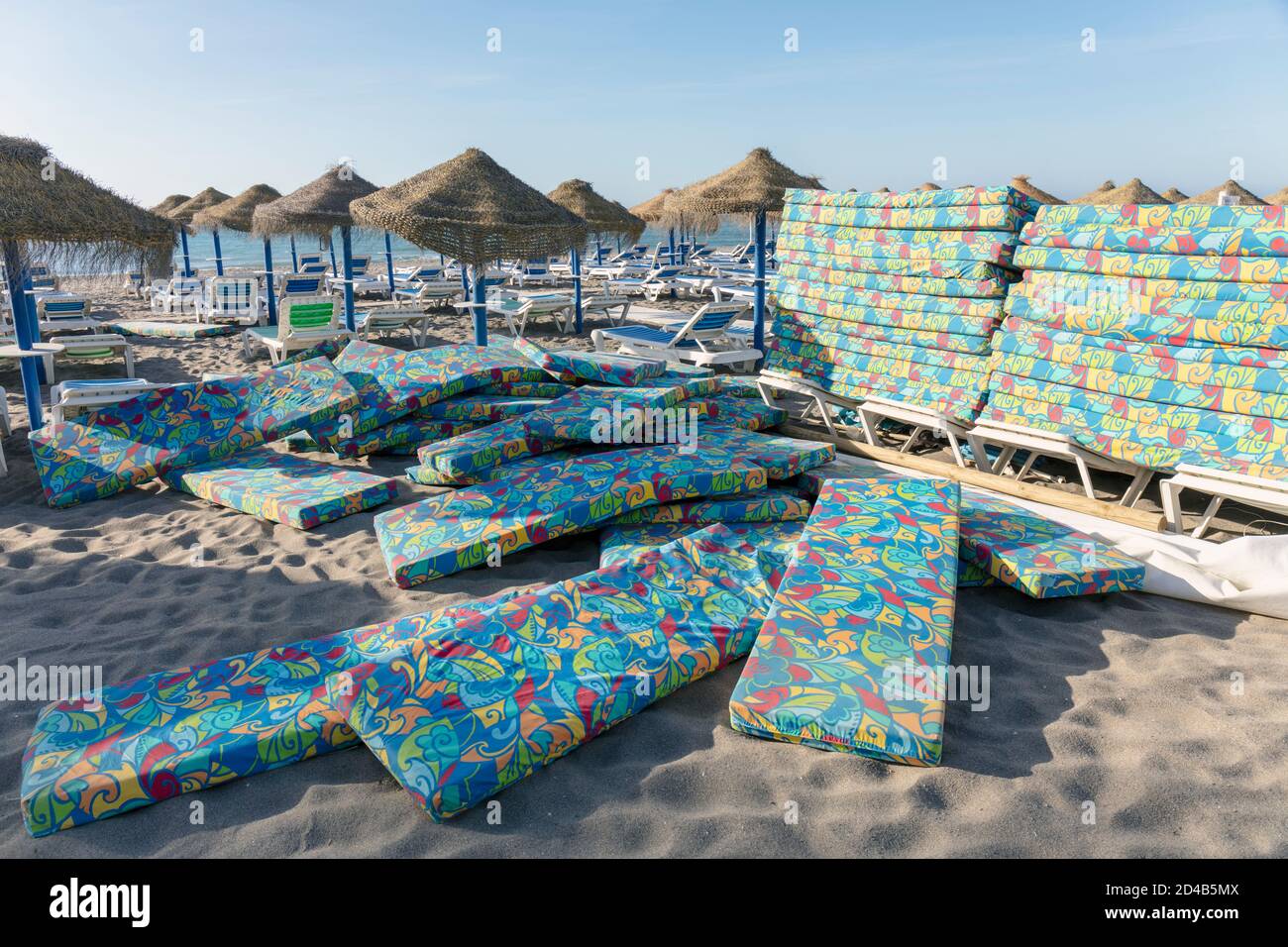Piles of sunbed mattresses on Costa del Sol beach waiting to be placed under sun umbrellas.  Torremolinos, Costa del Sol, Malaga Province, Andalusia, Stock Photo