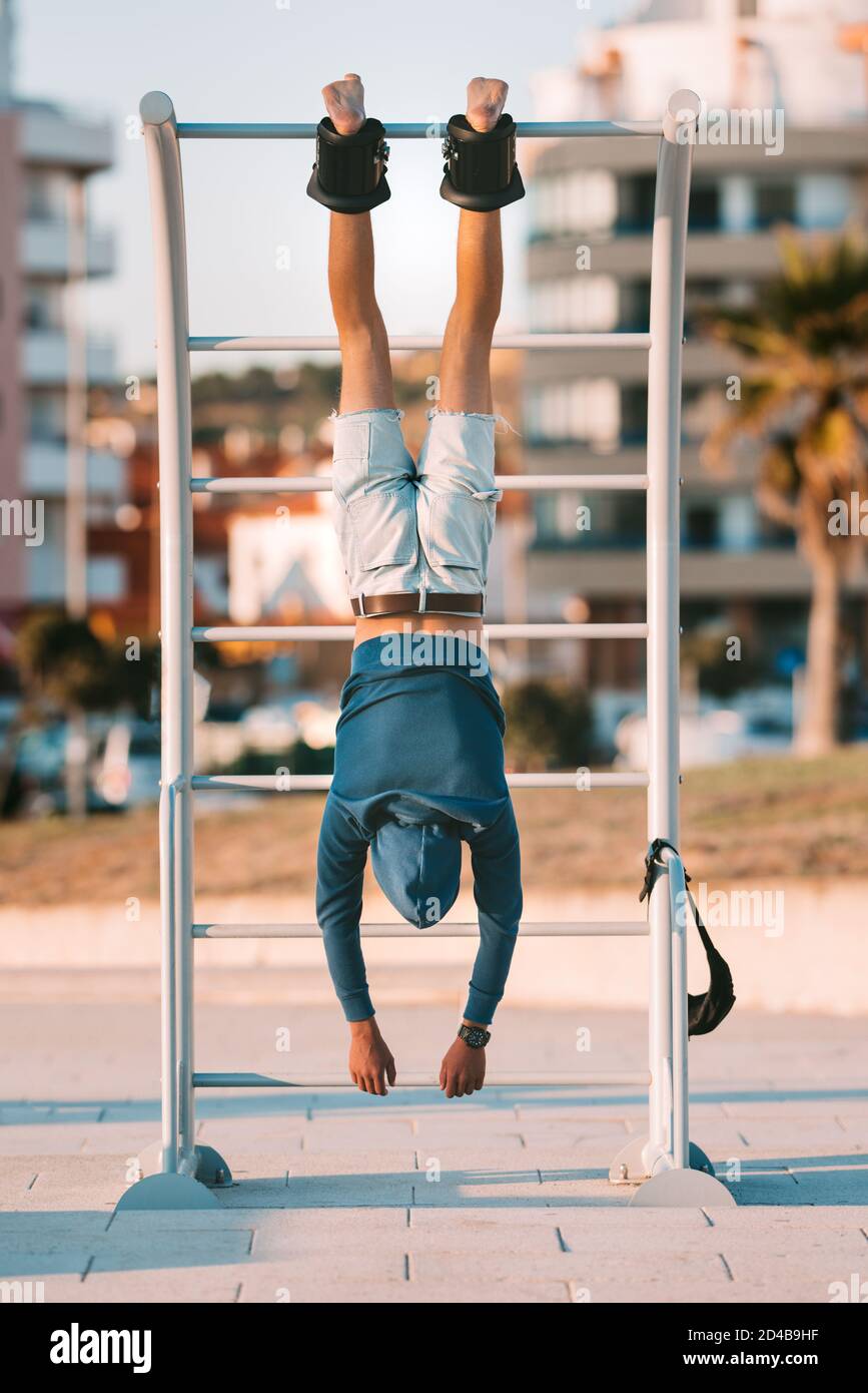 Man hanging upside down on the horizontal bar in anti gravity or inversion boots Stock Photo