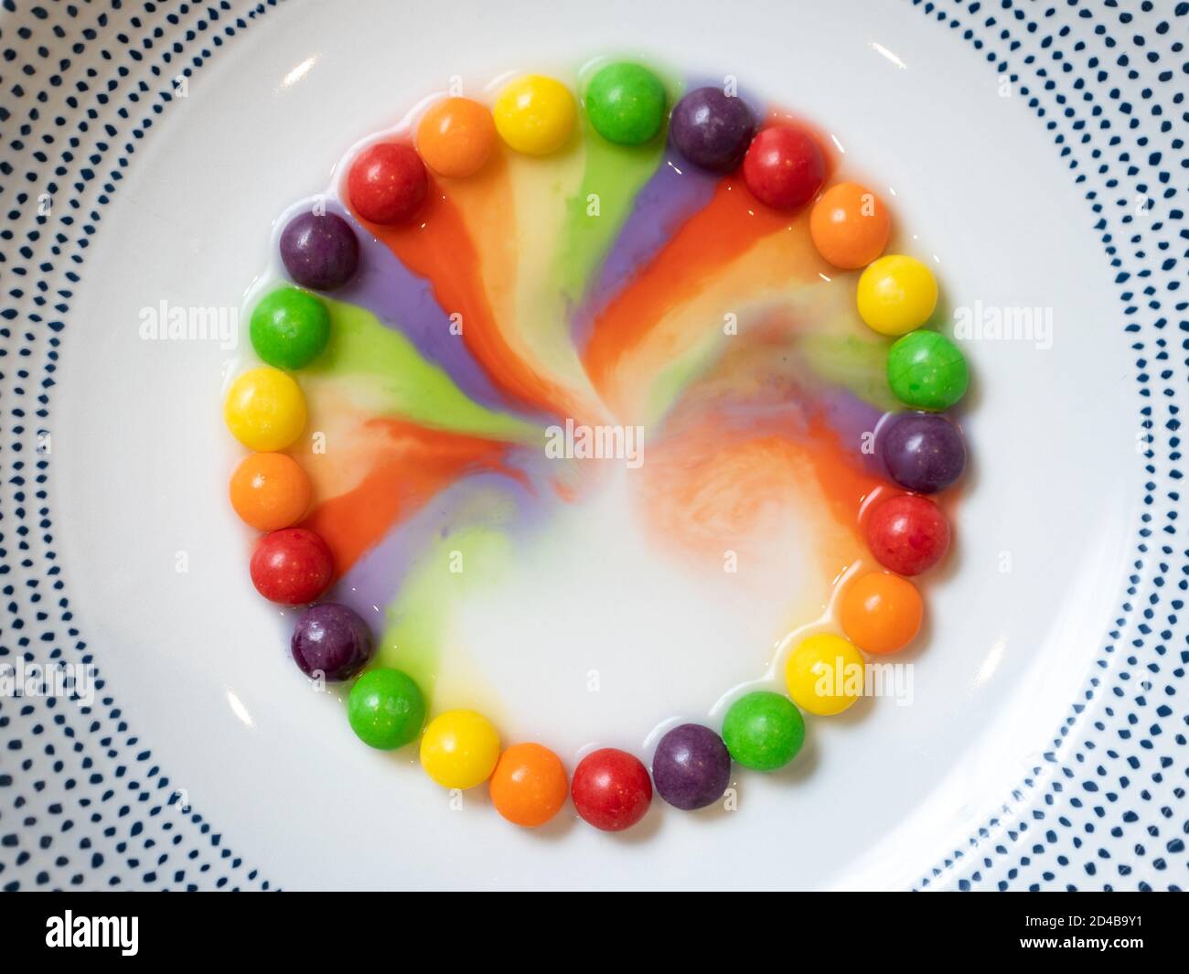 A circle of small candy in a white bowl with the colours slowly running into the middle Stock Photo