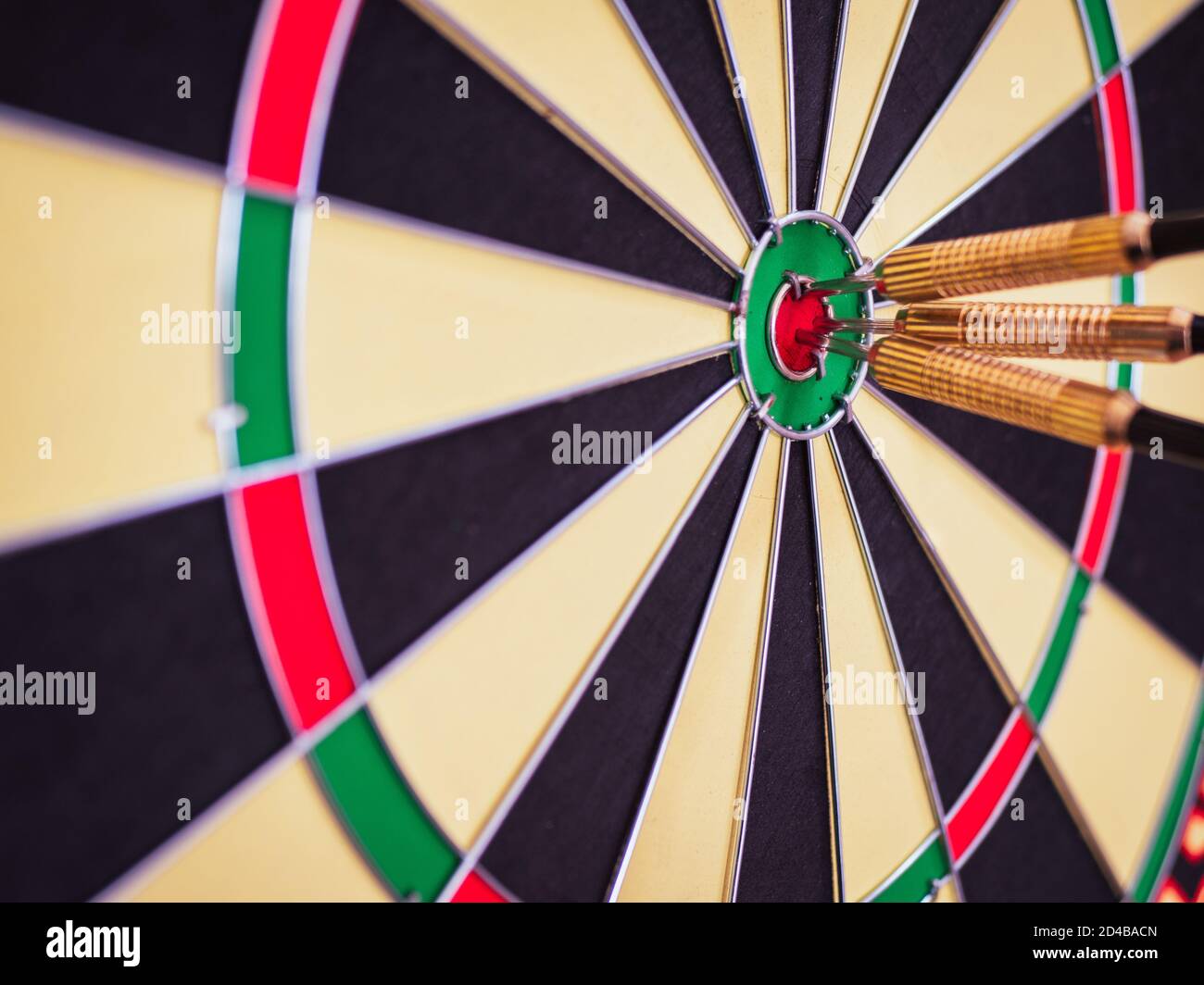 A closeup shot of three darts in the bullseye of a dart board Stock Photo