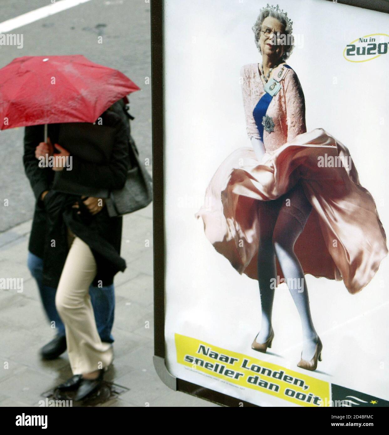 Pedestrians walk past a billboard advertising Eurostar's rail service showing British Queen Elizabeth II holding her dress in a [Marilyn Monroe] pose, in central Brussels, October 3, 2003. The picture, advertising a faster schedule for trains running from Brussels to London, can be seen all over the city. Stock Photo