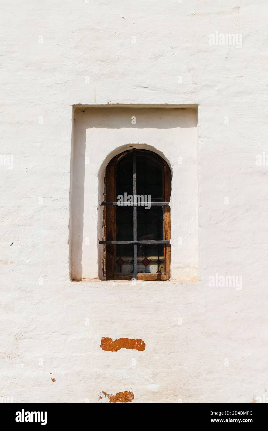 Small dark window in an ancient white stone wall. Vertical background photo texture Stock Photo